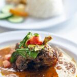 Delicious Indonesian beef rendang served with rice on a white plate.
